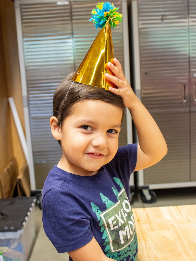 Image of a Child in a birthday hat celebrating at the Amazeum