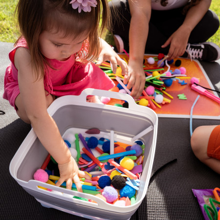 Young Girl Sorting Through Craft Parts In Tub