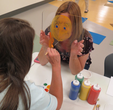 Someone Painting A Piece Of Glass To Look Like A Mask