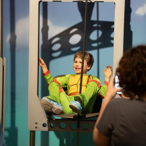 Boy In Ninja Turtle Costume Playing On Lift Exhibit