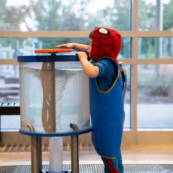 Boy In Spiderman Costume Playing With Whirlpool Exhibit