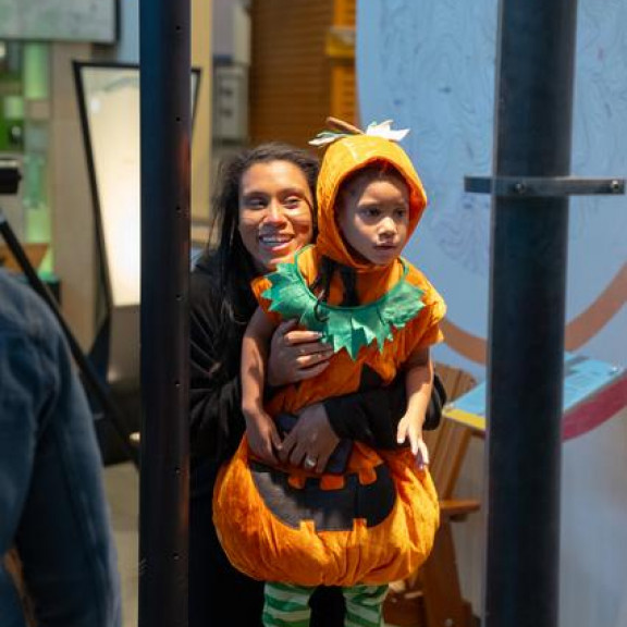 Mom Holding Young Boy In JackOLantern Costume