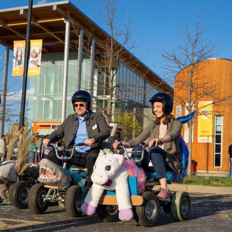 Two People Riding On Silly Motorized Carts