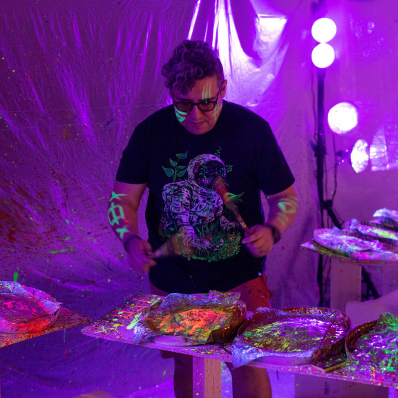 Man Painting Himself In Glow Paint Under Blacklight