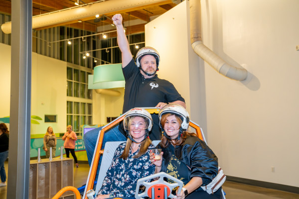 Three People With Helmets Riding Around In Cart