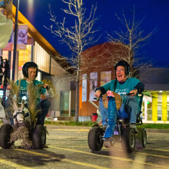 Two People Riding Silly Carts Outside