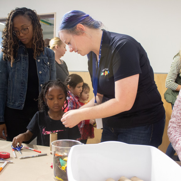 Amazeum Attendant Helping Girl With Her Cardboard Tube Project