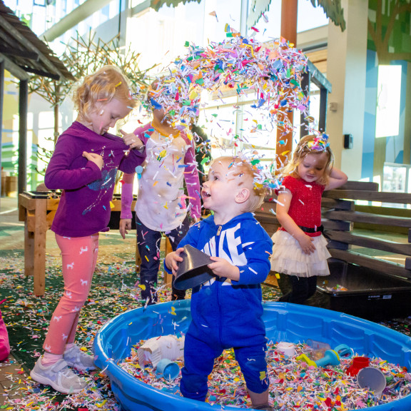 Small Child Playing With Confetti In Kiddie Pool