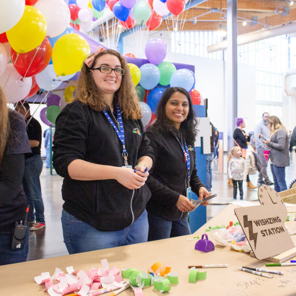 Two Employees Posing At Wishzing Station Table