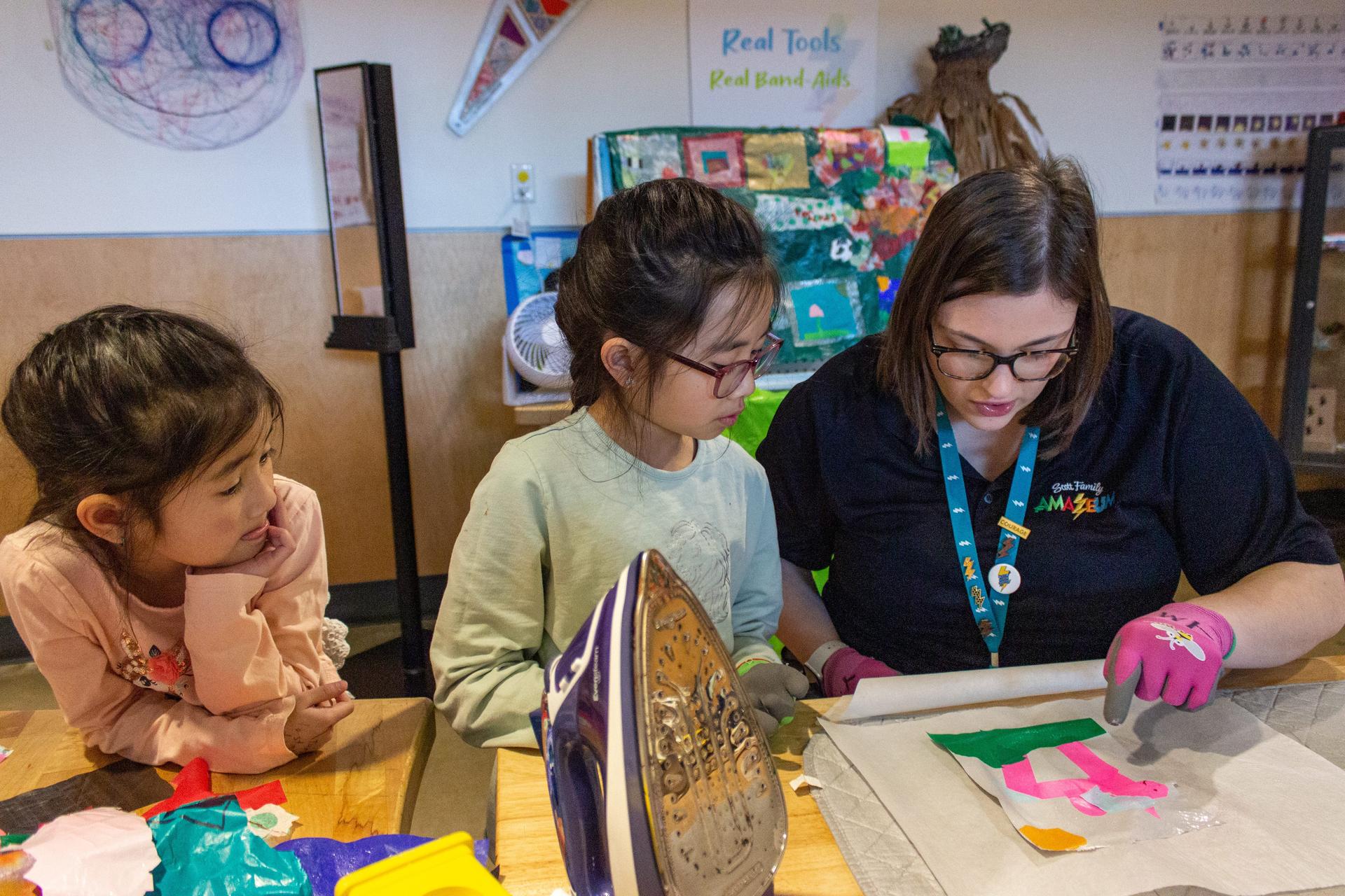 Amazeum Assistant Helping Two Children With Project