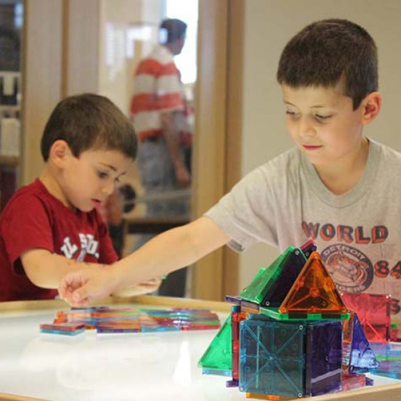 Two Boys Making Structures On Illuminated Table