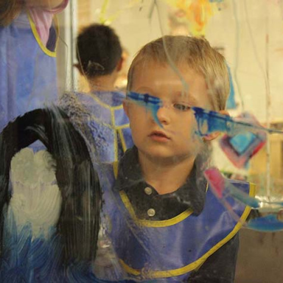 Young Boy Focused On His Glass Window Artwork