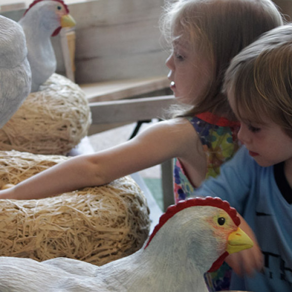 Children Tending To Fake Hens In The Chicken Coop