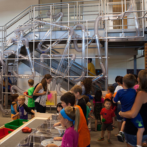 Children Standing In Front of Pneumatic Air Tube Exhibit