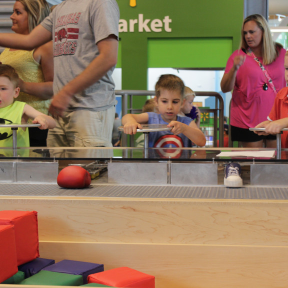 Young Boy Turning Wheel To Interact With Exhibit