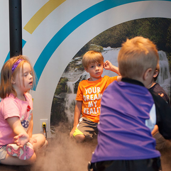 Group Of Children Sitting In Artificial Fog