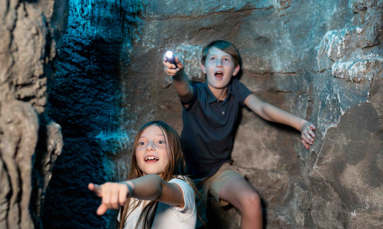 Two Children Exploring The Amazeum Cave