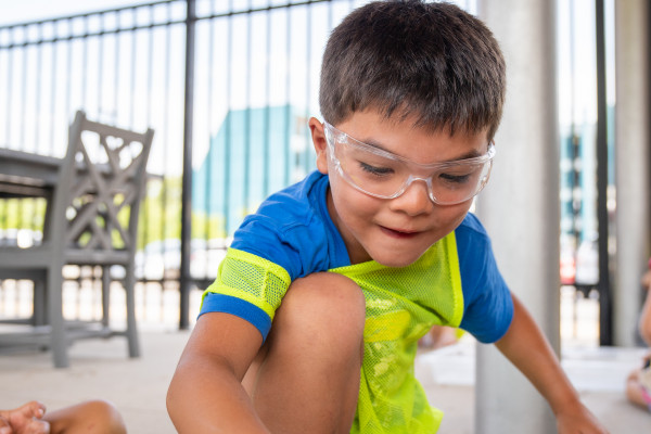 Young Boy Doing A Chemistry Experiment Outside The Amazeum