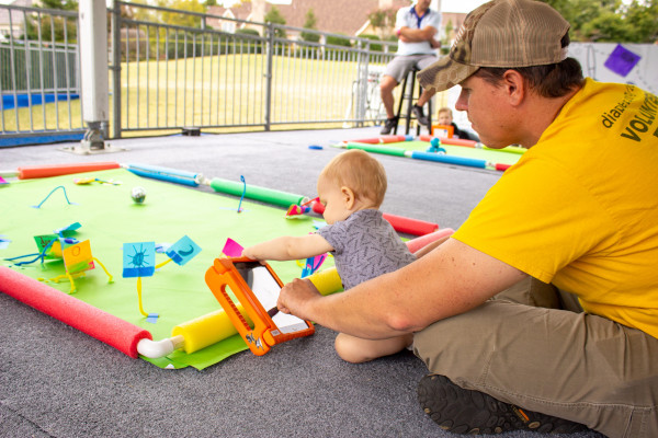 Parent Helping Baby Play At Exhibit For Small Children