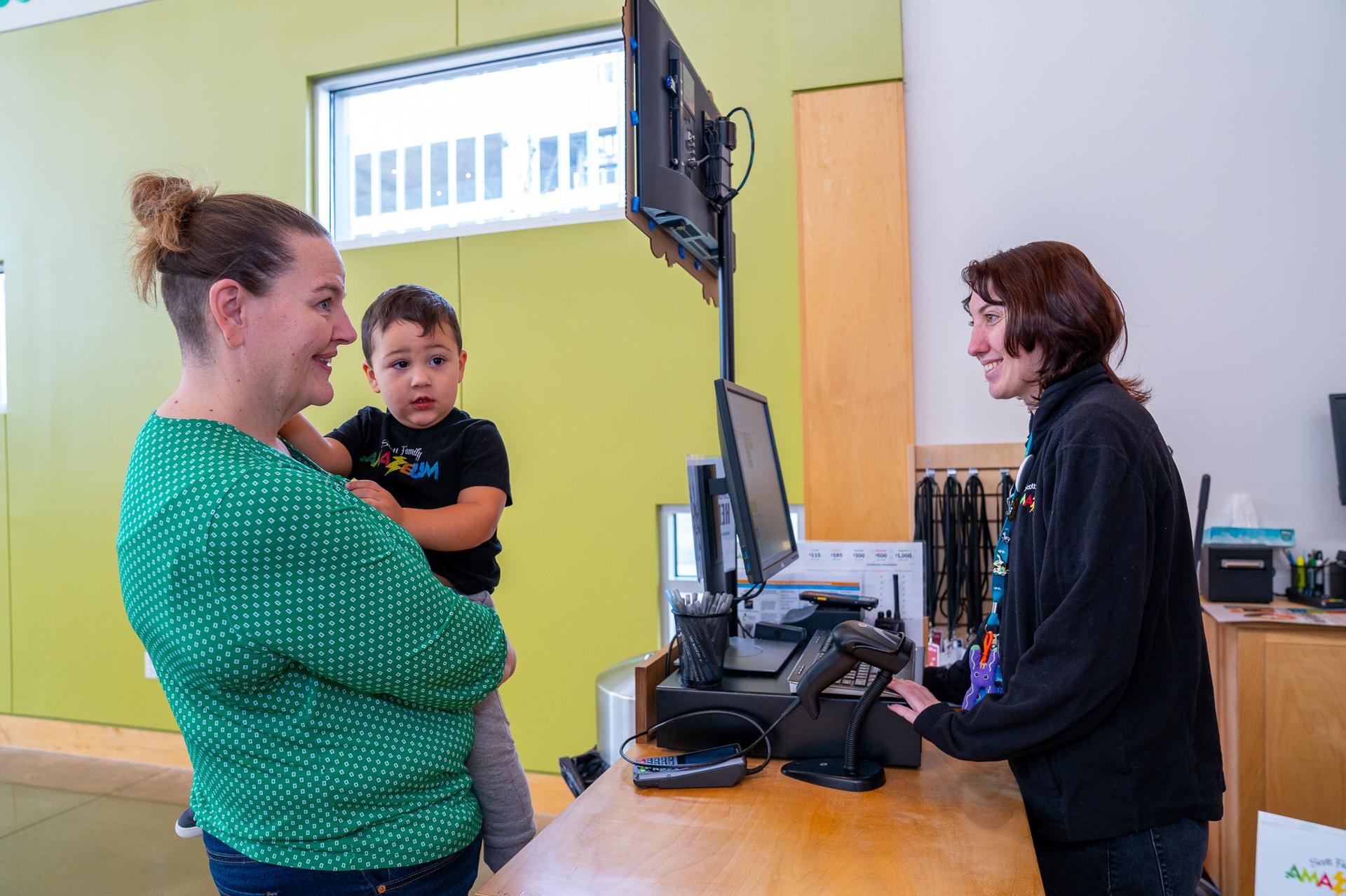 Mom With Her Child Checking In At Amazeum Front Desk