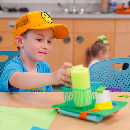 Boy In Smiley Hat Working On Foam Noodle Project