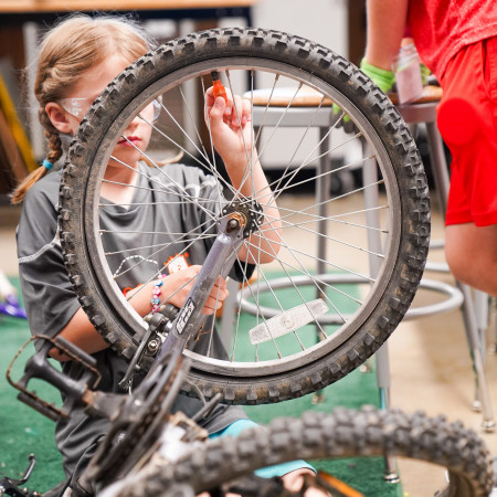 Girl Checking The Air Pressure Of Her Bicycle Tire