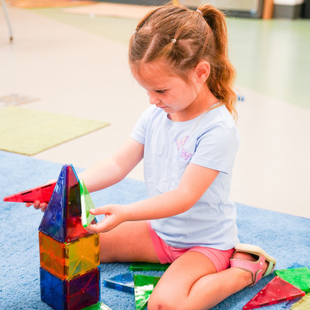 Girl Playing With Magna Tiles On Large Rug