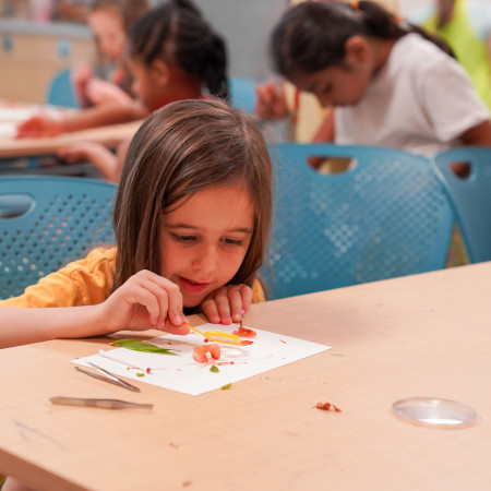 Girl Using Magnifying Glass To Inspect Her Artwork