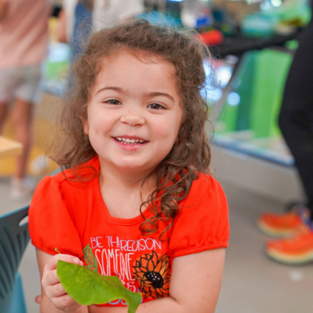 Girl With Green Leaf In Her Hand Smiling For Camera