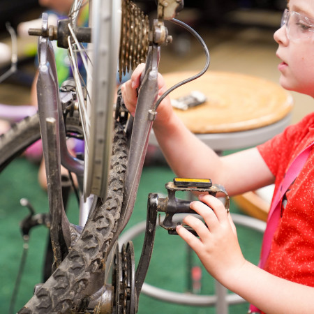 Young Boy Inspecting Wheel On Bicycle