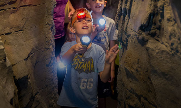 Two Boys With Flashlights In The Amazeum Cave